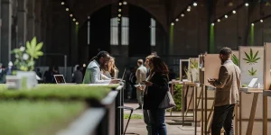 Des visiteurs explorent des présentations de produits à base de cannabis et échangent lors d’une grande exposition professionnelle.