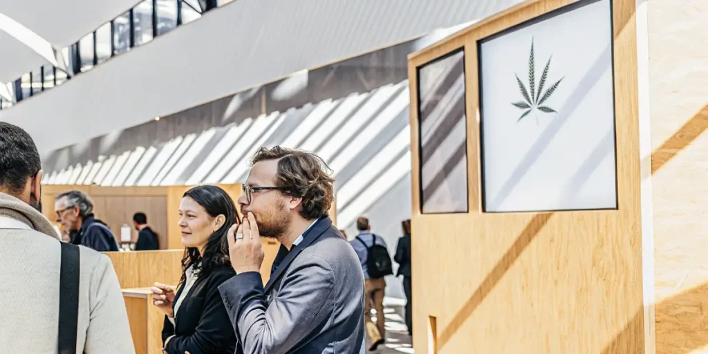Des professionnels échangent devant un stand moderne lors d’un salon dédié à l’industrie du cannabis.