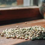 un tas de graines de cannabis posé sur une table en bois à la lumière naturelle.