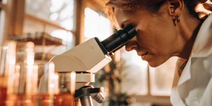 Scientifique observant un échantillon au microscope dans un laboratoire.