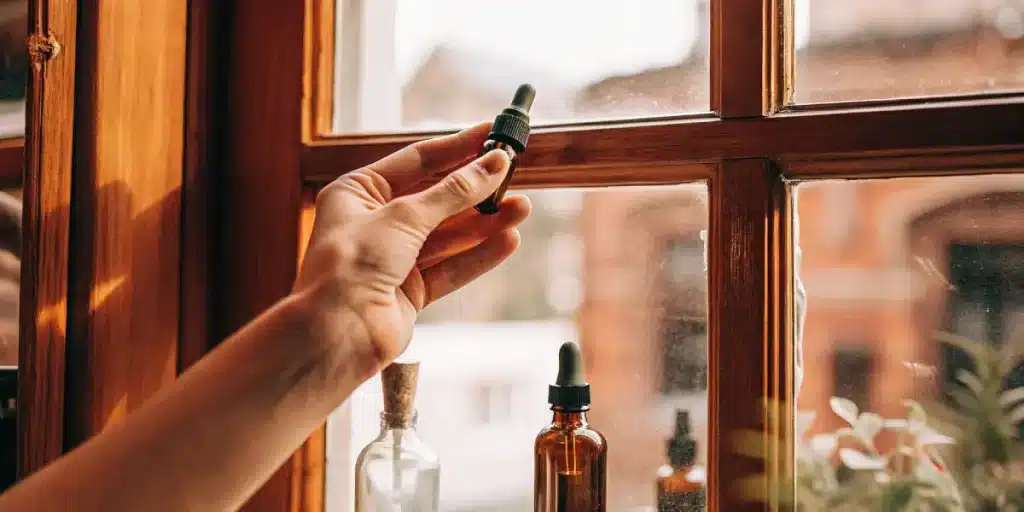 main tenant un flacon d’huile de cannabis près d’une fenêtre